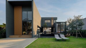 Ein modernes Haus mit großem Panoramafenster, einem Schwimmbad und einem Rasenstück.