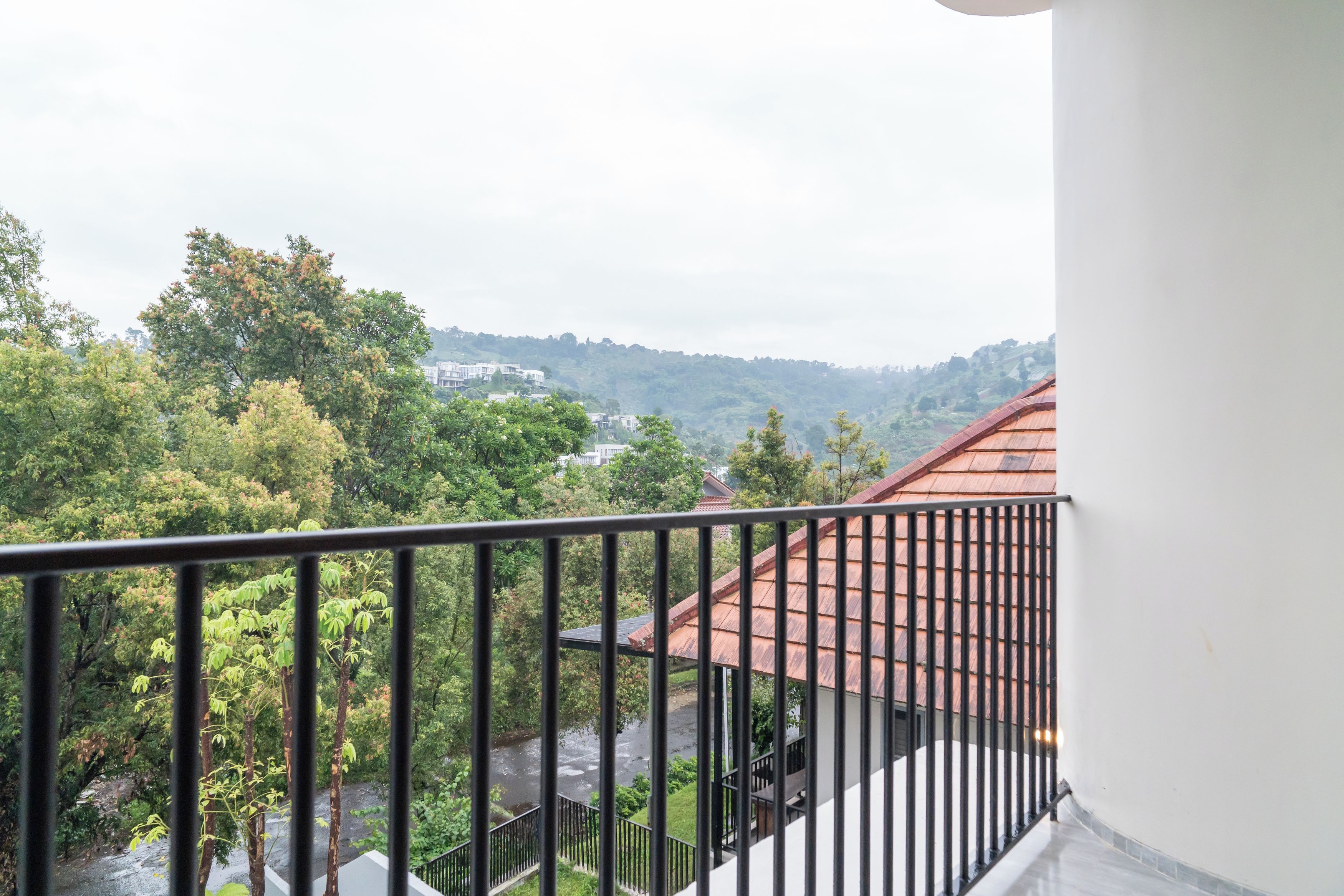 A balcony with a metal railing overlooking a residential area with houses and trees.