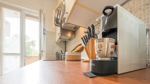 A kitchen with a coffee maker, a cup, and a bread box on the counter.
