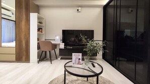 Un saló modern amb televisió plana, una taula de centre amb un llibre i una planta.