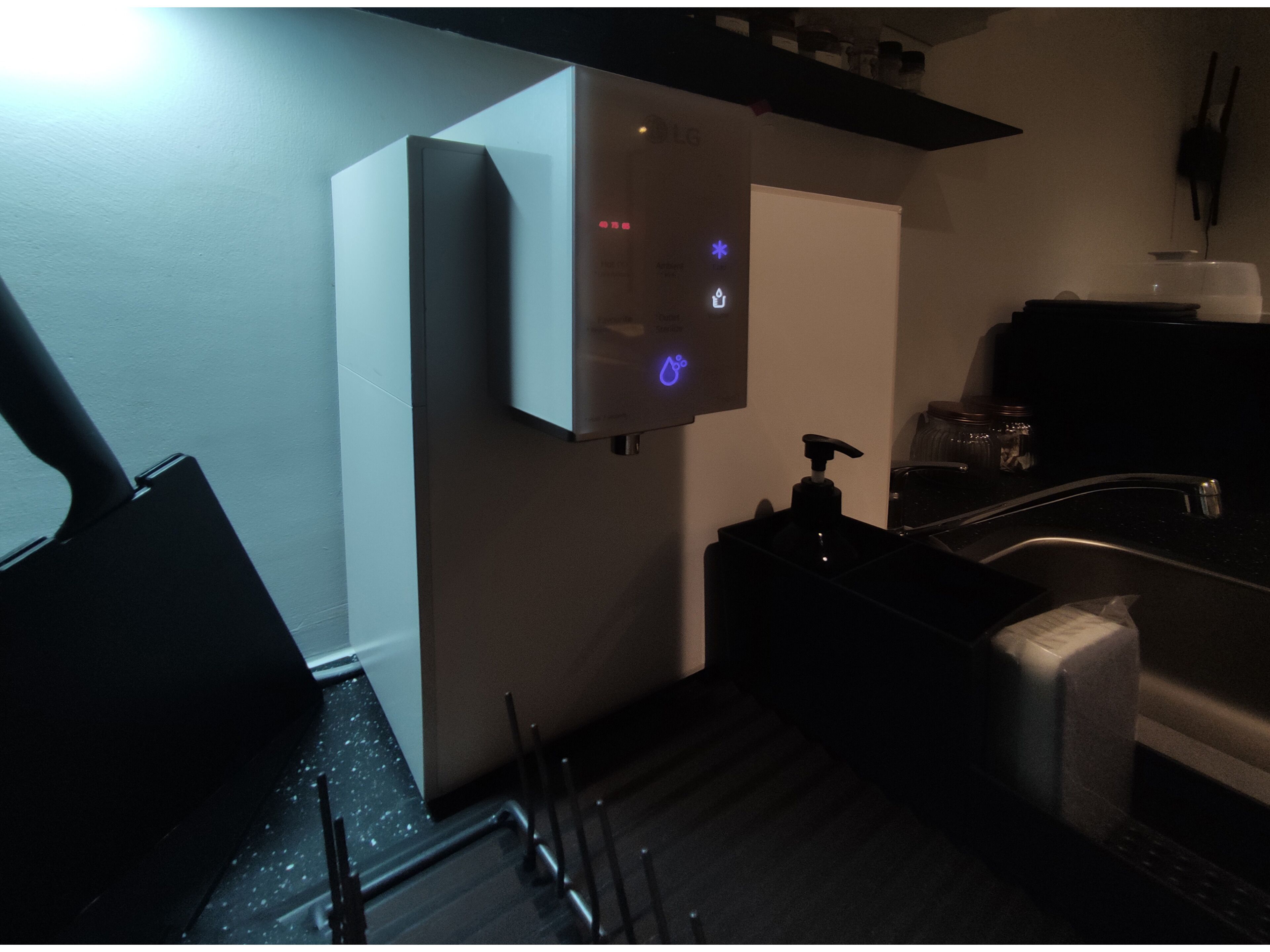 A modern bathroom with a built-in sink, a mirror, and a soap dispenser.