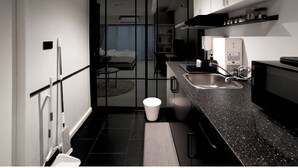 Habitació d'hotel compacta amb cuineta, un llit i un bany.