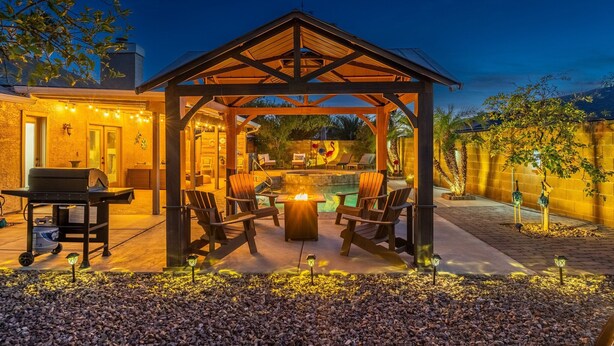 A covered patio area with a fire pit, seating, and a grill. - Great Location! Walk to State Farm Stadium! Heated Pool & Spa! (Glendale)