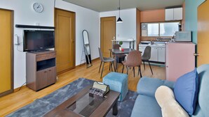 A modern living room with a sofa, coffee table, TV, and dining area. - MOVE 8 (Abashiri)