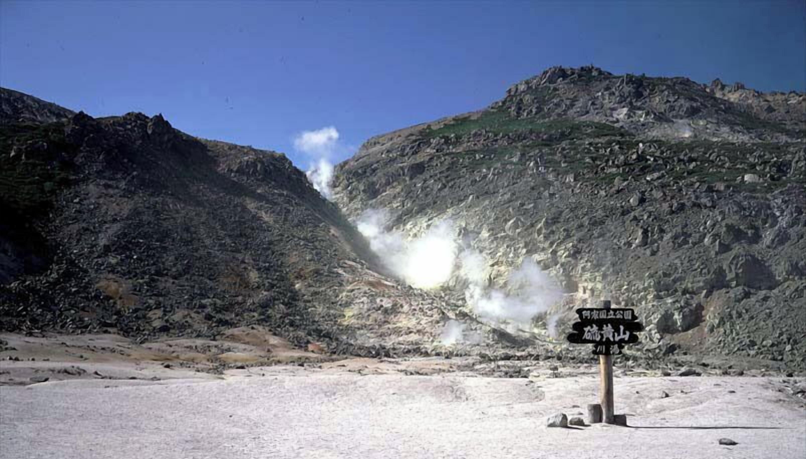 A mountainous landscape with a signpost in the foreground.