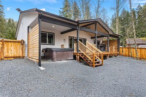 A modern house with a covered porch, a hot tub, and a wooden deck.