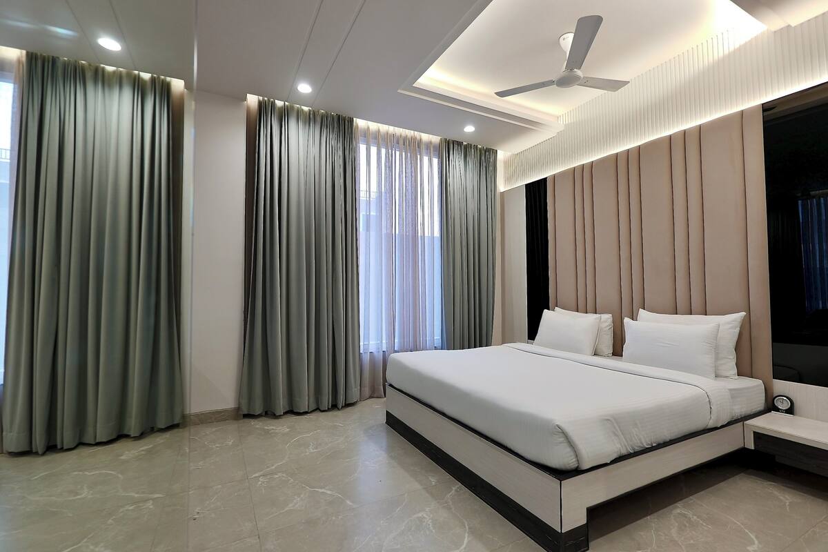 Un dormitorio moderno con una cama grande, un ventilador de techo y una mesita de noche.