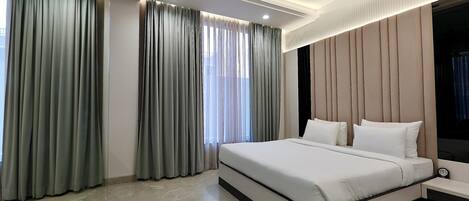 A modern bedroom with a large bed, a ceiling fan, and a nightstand.