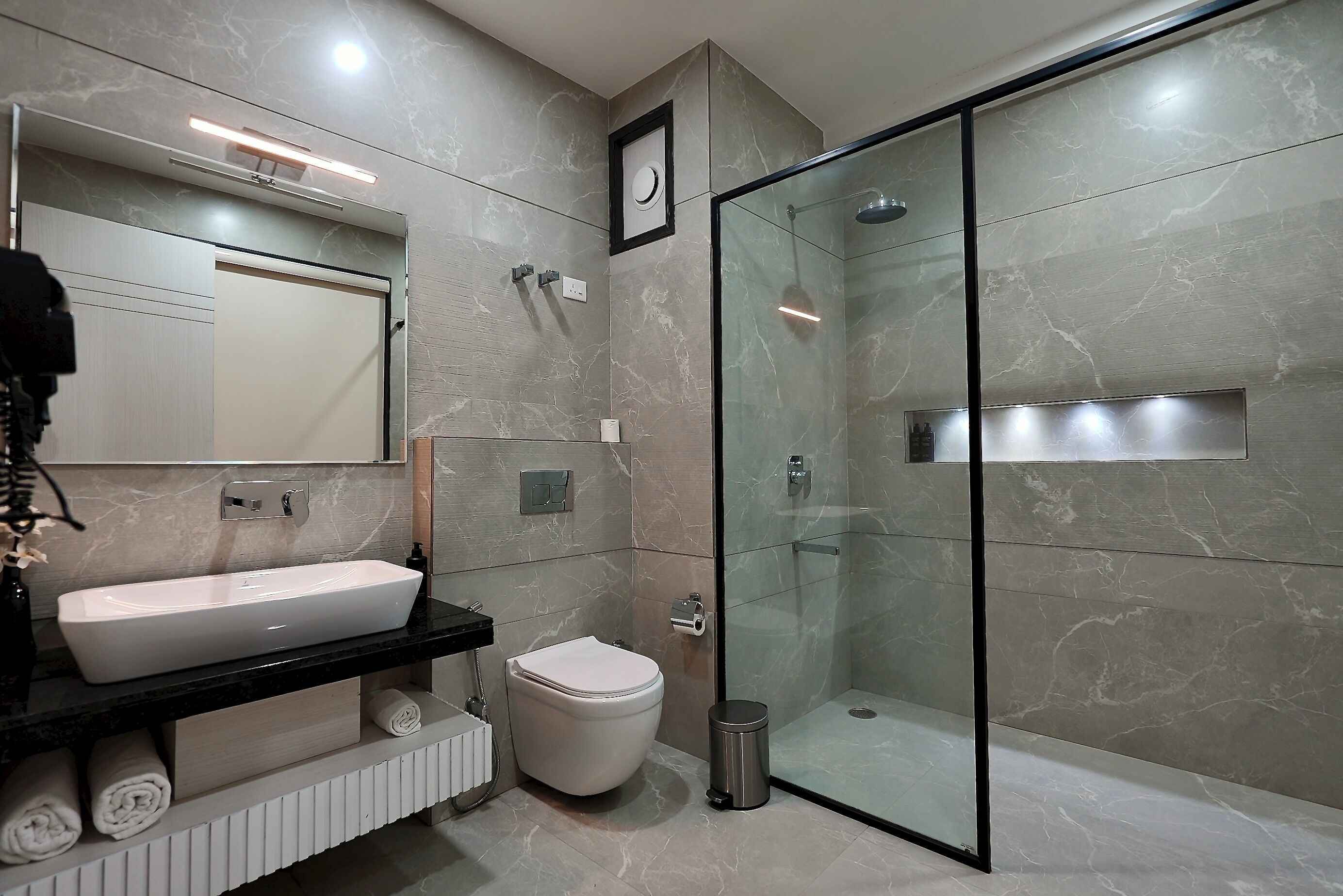 A modern bathroom with a glass-enclosed shower, a white sink, and a toilet.