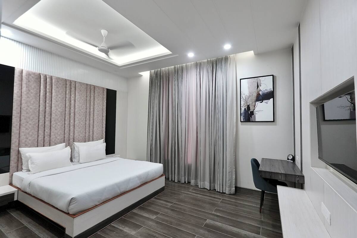 Una habitación de hotel moderna con una cama grande, un escritorio y una lámpara de techo.