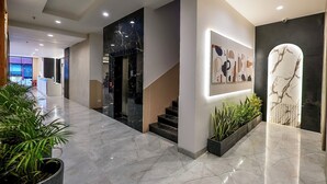 A modern hotel lobby with marble flooring, a staircase, and potted plants. - Elinor Hotel (Agra)