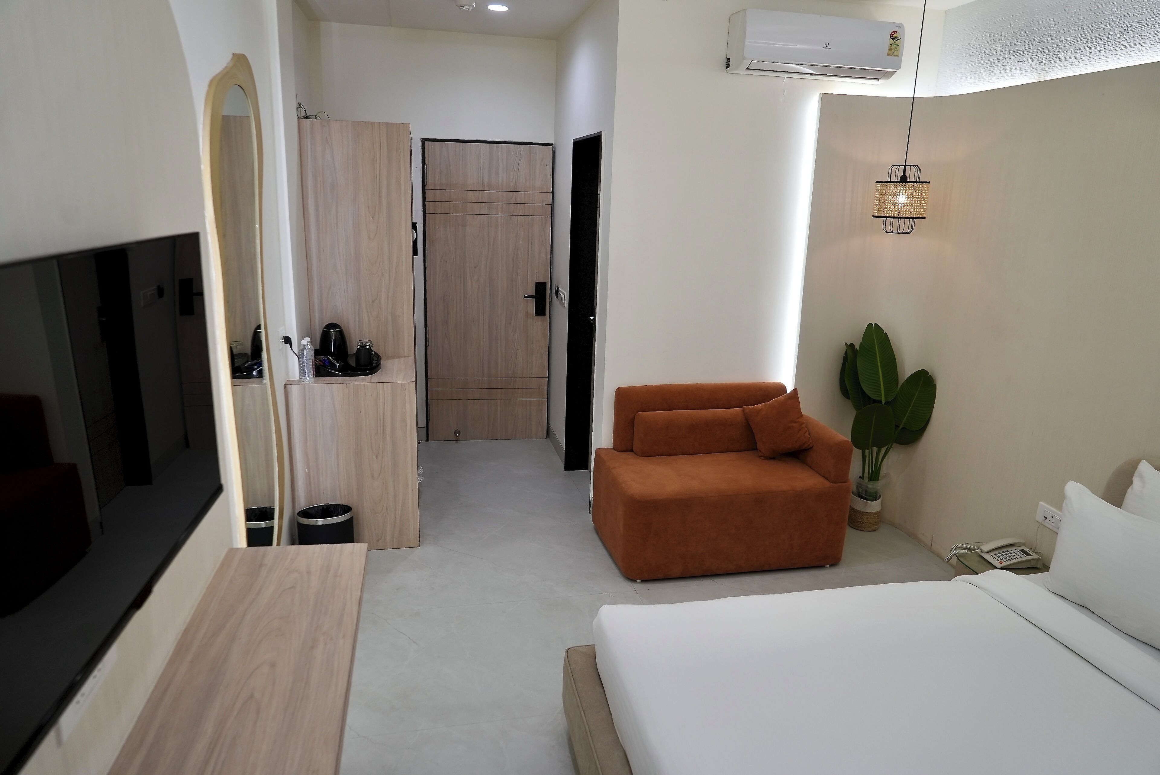 Une chambre d’hôtel avec un lit, un canapé, une télévision, une armoire et une plante en pot.