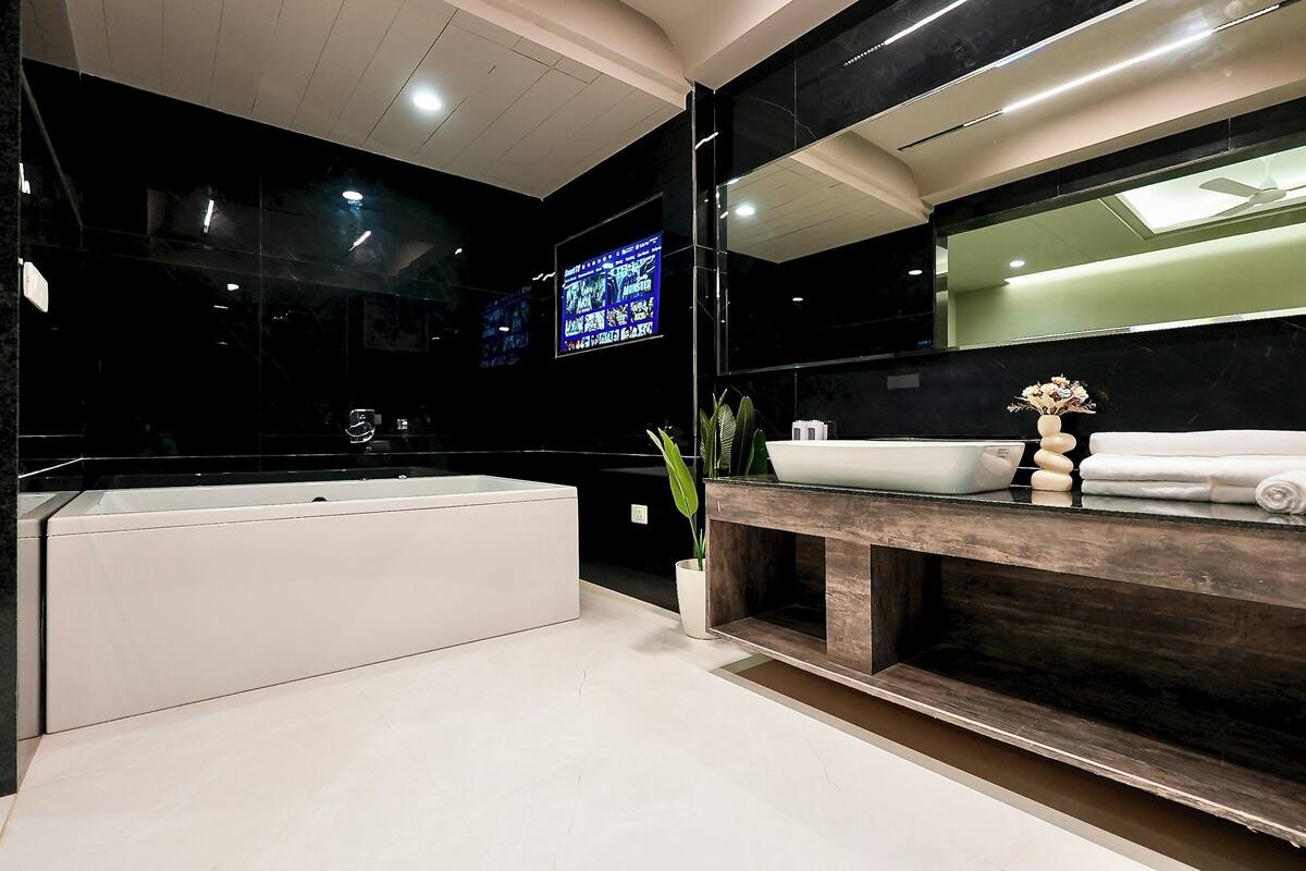 Un baño moderno con una bañera grande, un tocador de madera y un espejo amplio.