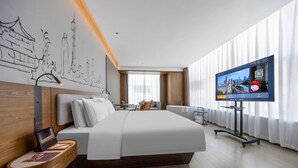 A modern hotel room with a large bed, a desk with a laptop, a TV on the wall, and a cityscape mural. - UrCove by Hyatt Guangzhou Huadu Baiyun International Airport (Guangzhou)