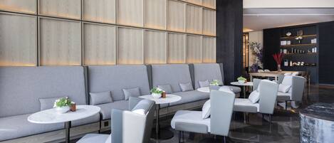 Eine moderne Lobby mit Sitzgelegenheiten, einem Empfangsbereich und einem Bücherregal.