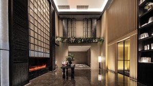 A modern lobby with a fireplace, a reception desk, and a bookshelf. - UrCove by Hyatt Guangzhou Huadu Baiyun International Airport (Guangzhou)