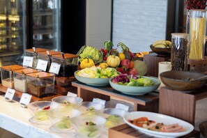 Un buffet con diversi cibi e contenitori, tra cui frutta, verdura e piatti pronti.