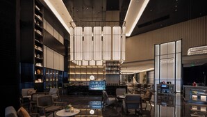 A modern hotel lobby with a bar area, seating arrangements, and a reflective floor. - UrCove by Hyatt Guangzhou Huadu Baiyun International Airport (Guangzhou)