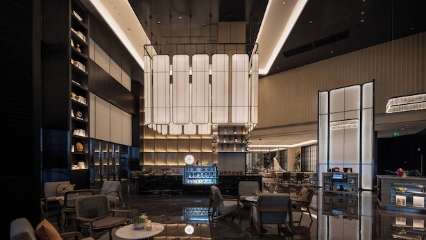 A modern hotel lobby with a bar area, seating arrangements, and a reflective floor. - UrCove by Hyatt Guangzhou Huadu Baiyun International Airport (Guangzhou)