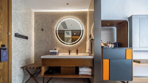 A modern bathroom with a round mirror, wooden vanity, and a built-in cabinet. - UrCove by Hyatt Guangzhou Huadu Baiyun International Airport (Guangzhou)