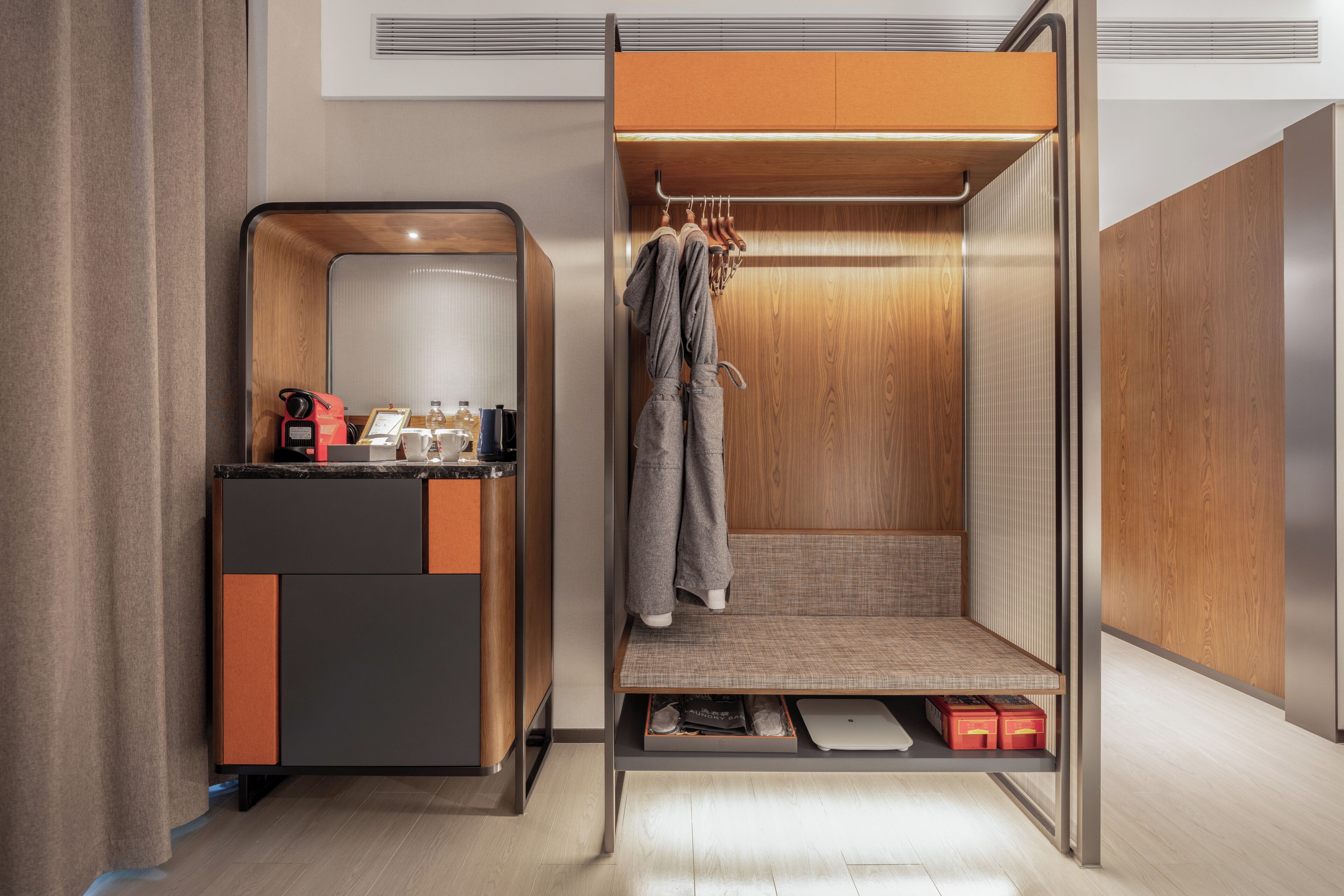 Une pièce compacte dotée d’une armoire intégrée, d’un petit coin salon et d’un plan de travail avec une bouilloire et d’autres accessoires.