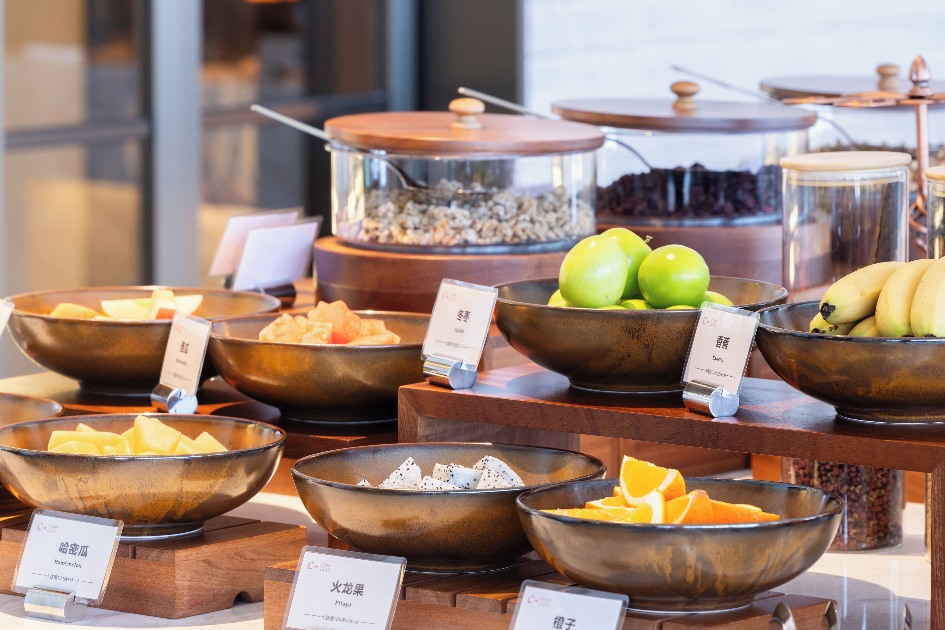 A buffet with various food items in bowls, including fruits and possibly cereals.