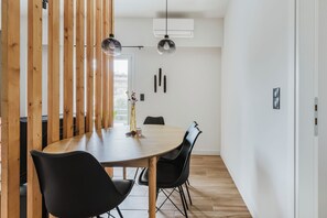 Una sala da pranzo moderna con un tavolo rotondo in legno, sedie nere e illuminazione a sospensione.