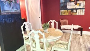 A dining area with a round table and chairs, a red accent wall, and a painting. - Downtown+FreeParking+Wifi Main St. Ste 101 (Eureka Springs)