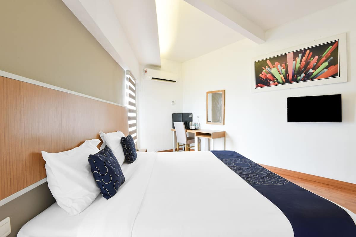 A hotel room with a large bed, a desk, a chair, a flat-screen TV, and a painting on the wall.