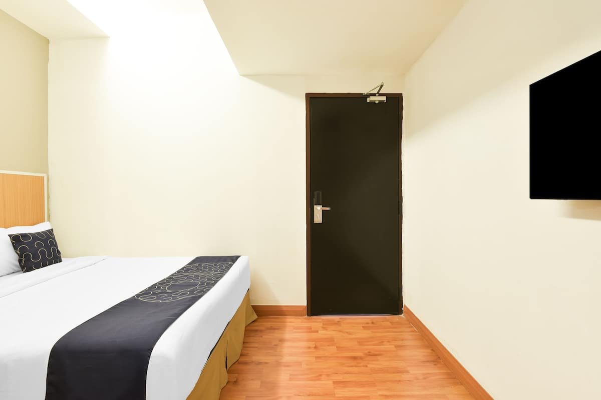 A hotel room with a bed, a door, and a mounted TV.