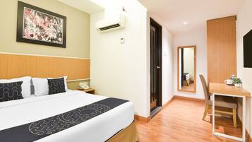 A hotel room with a bed, bedside table, and a desk with a chair.