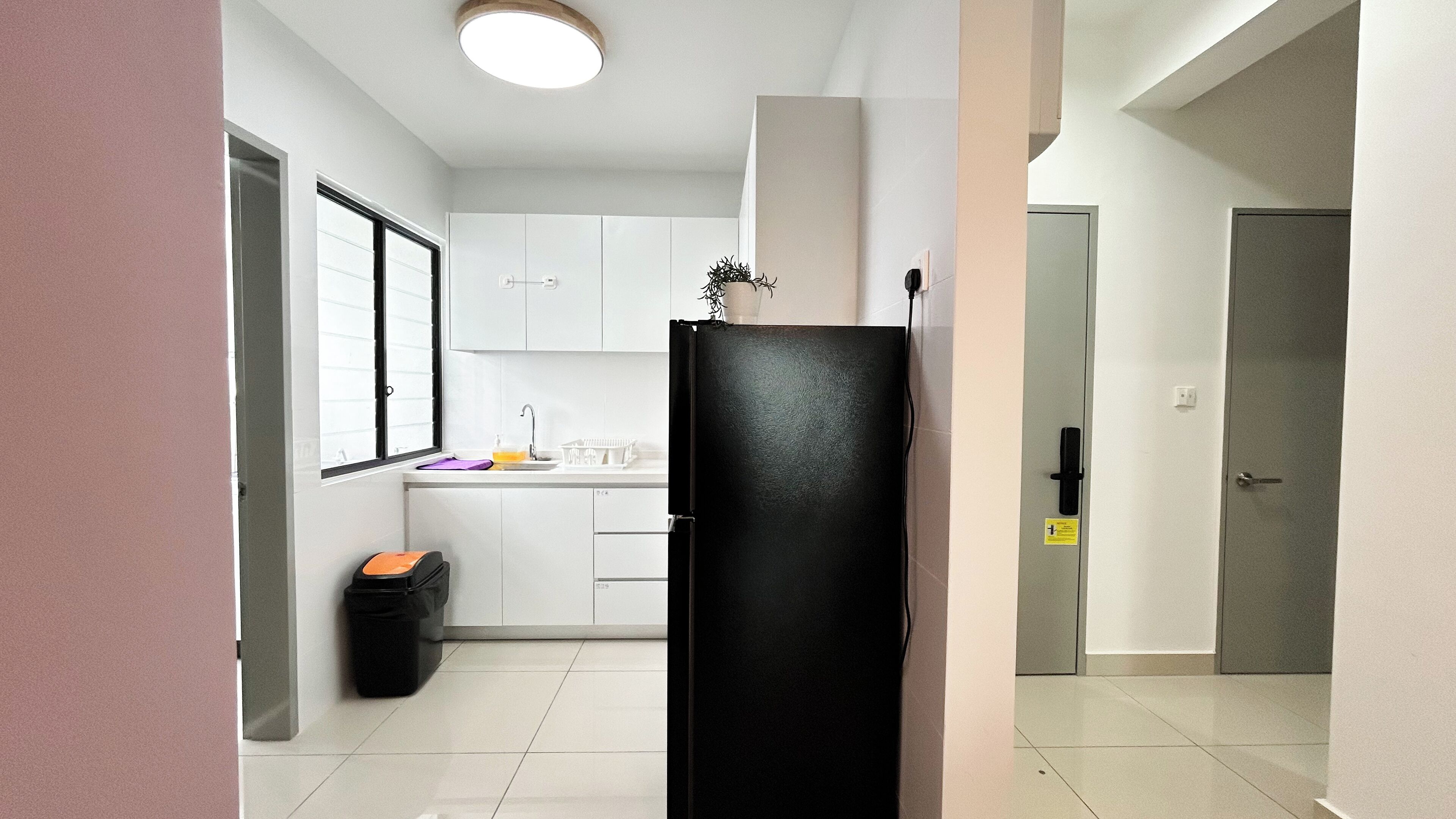 A modern kitchen with white cabinets, a black refrigerator, and a small sink.