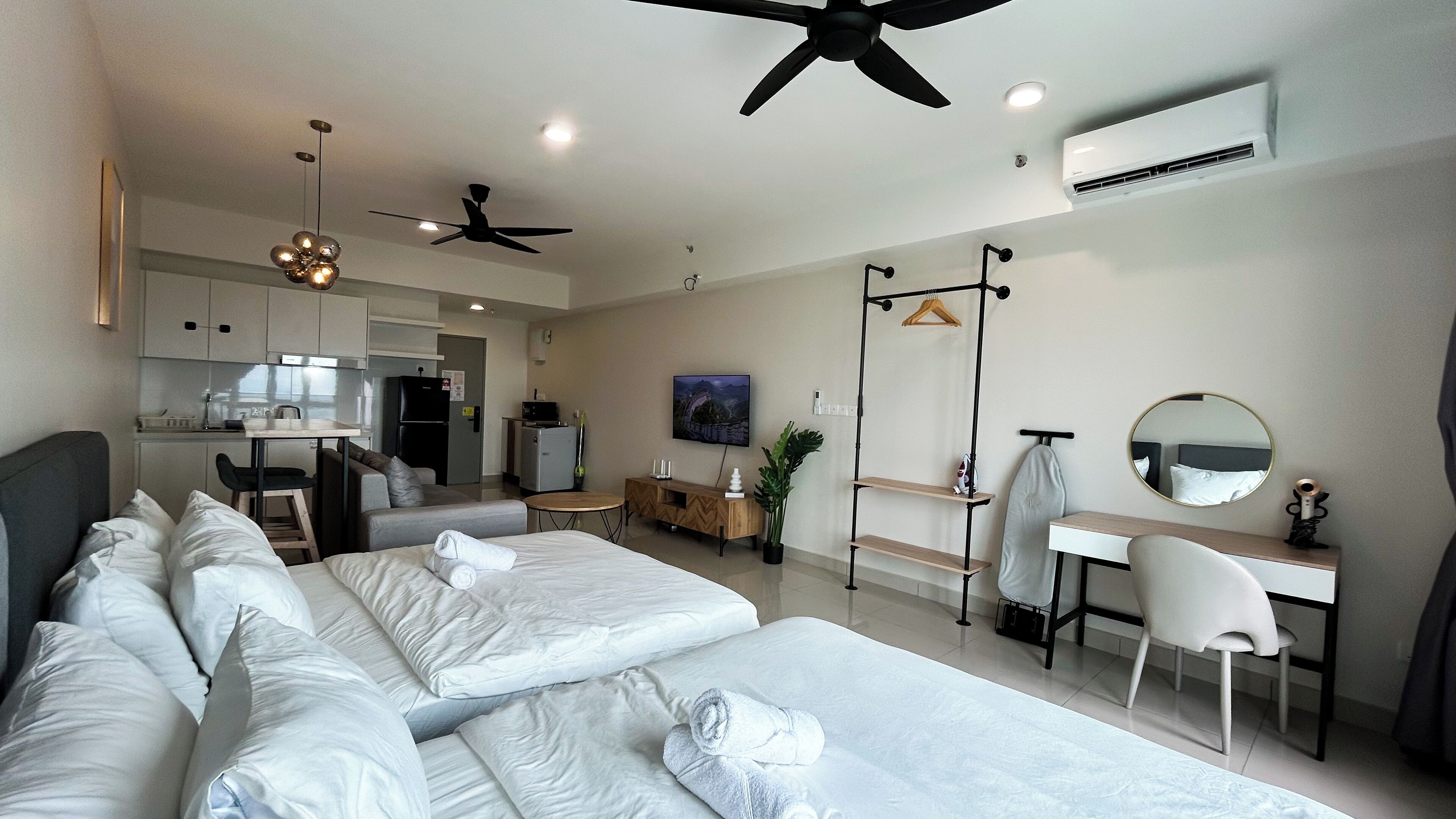 Una habitación de hotel moderna con dos camas, un escritorio, una silla, un televisor y una kitchenette.