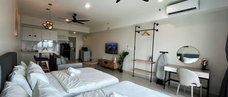 Una habitación de hotel moderna con dos camas, un escritorio, una silla, un televisor y una kitchenette.