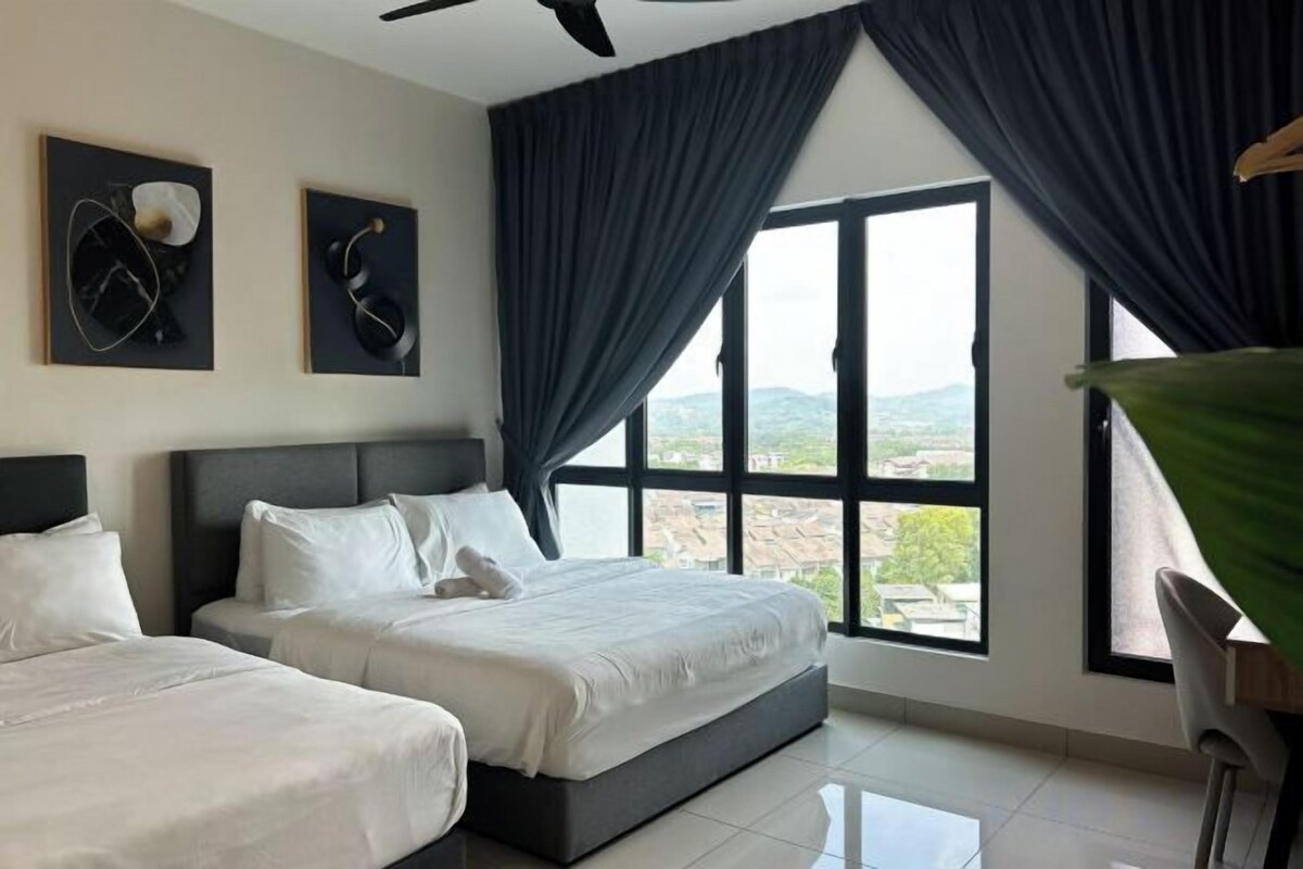 Habitación de hotel con dos camas, un ventanal con cortinas y vistas al exterior.