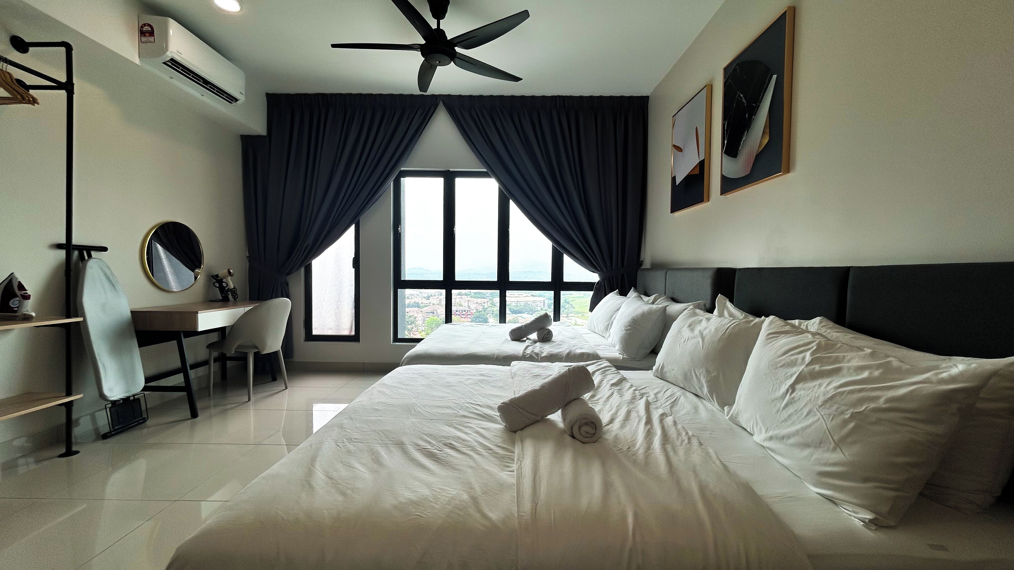 A hotel room with a bed, a desk, a chair, a ceiling fan, and a window with curtains.