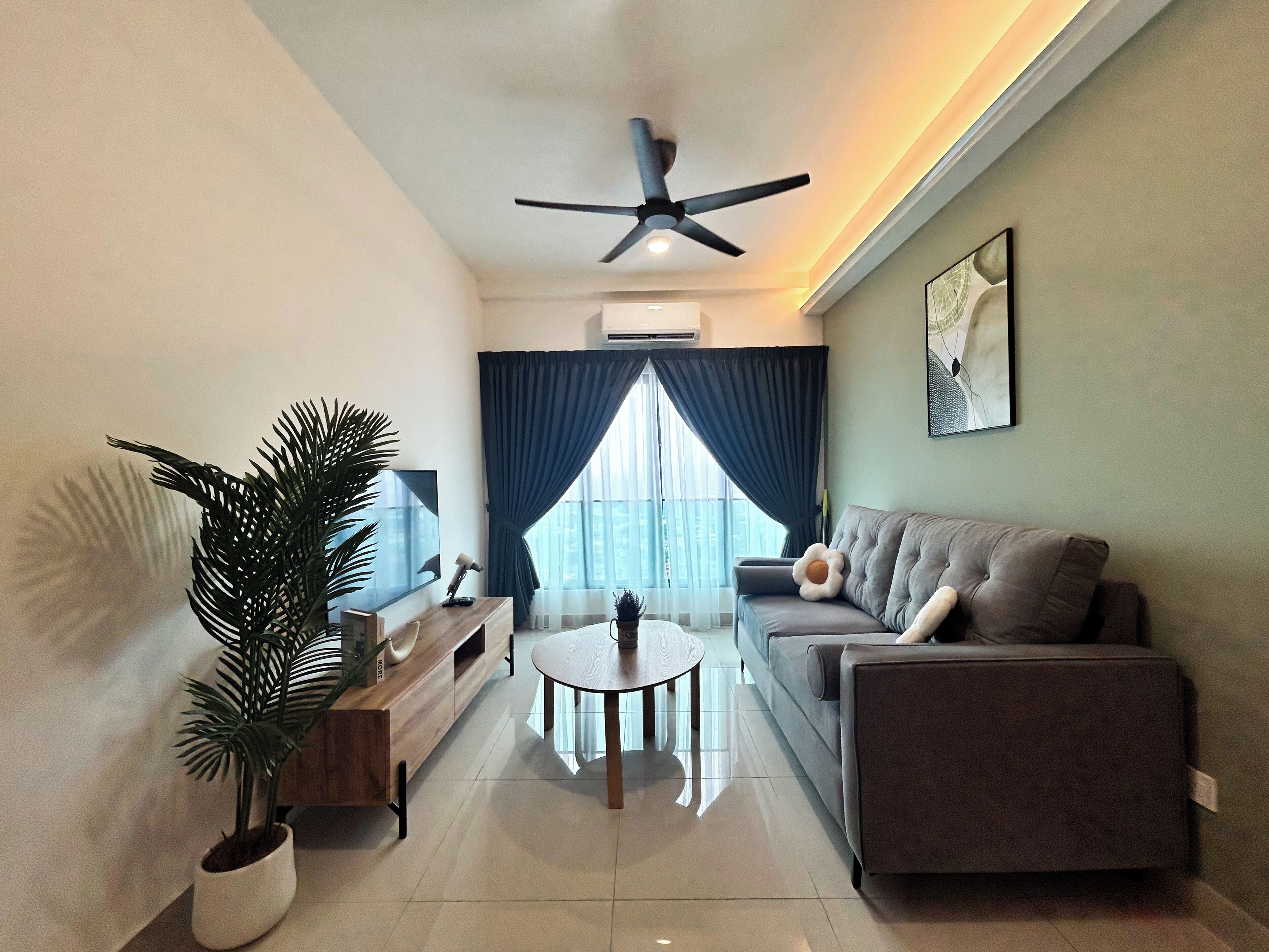Un salon moderne avec un canapé, une table basse, un téléviseur et un ventilateur de plafond.