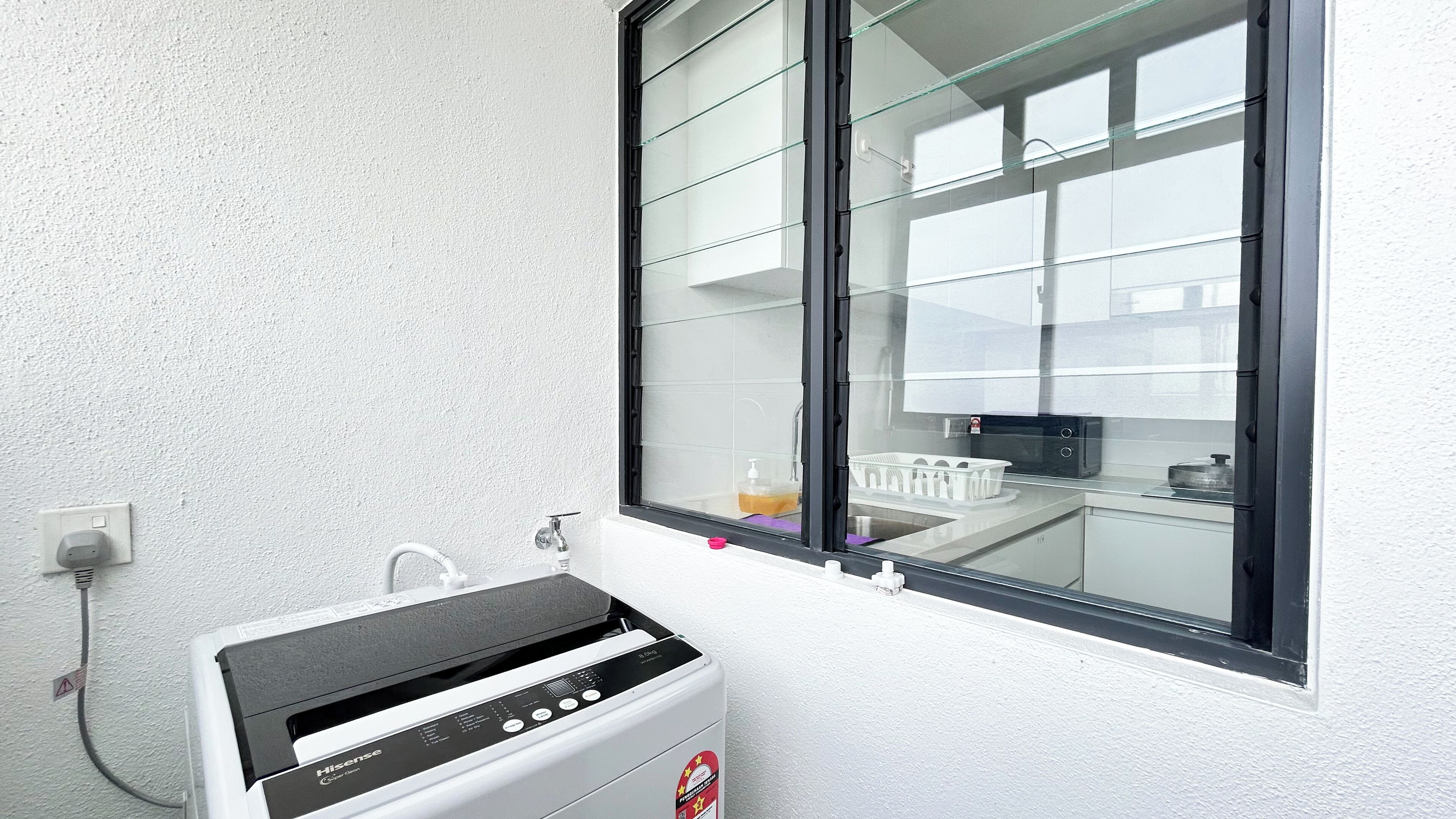 A compact kitchen with a built-in oven, a window with blinds, and a visible power outlet.