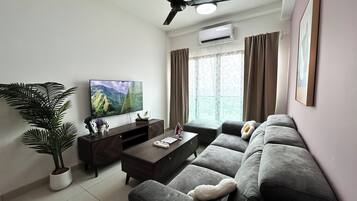 A modern living room with a flat-screen TV, a sofa, a coffee table, and a potted plant.