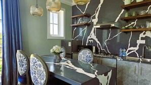 A modern kitchen with a marble backsplash, pendant lights, and a dining area with patterned chairs. - Private Villa by the Tea Estate (Nuwara Eliya)