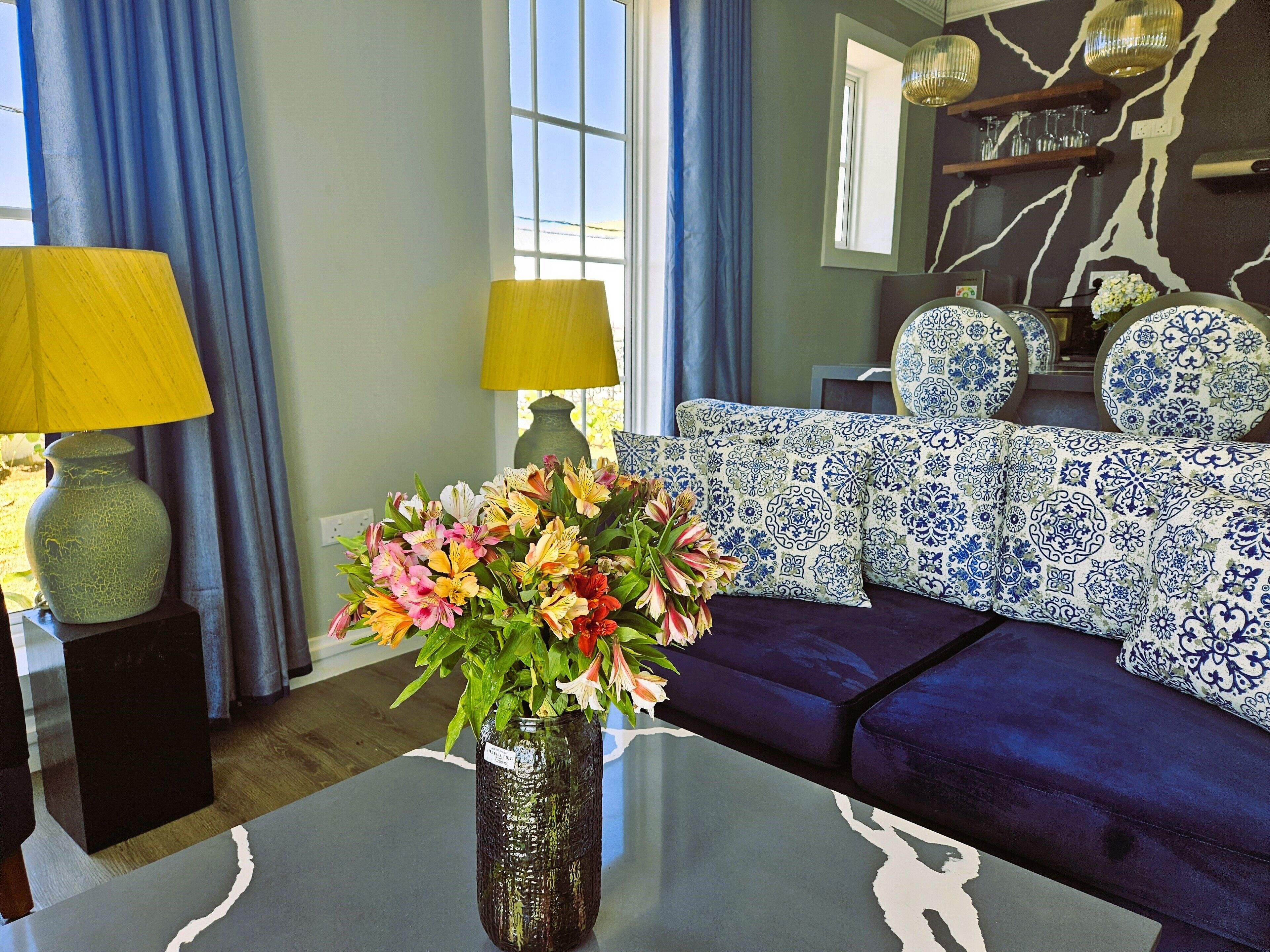 A living room with a dark blue sofa, a vase with flowers, and two lamps on side tables.