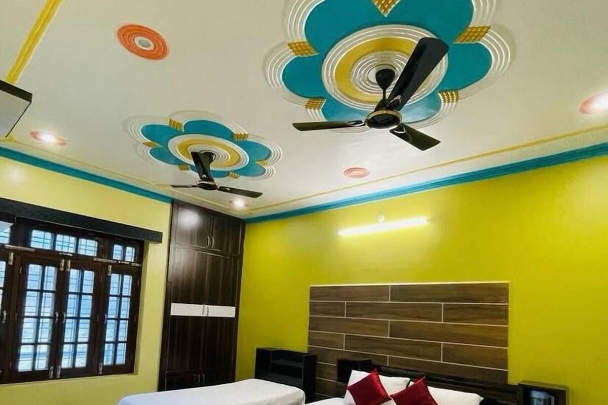 A hotel room with two beds, a ceiling fan, and a window with bars.