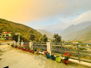 Una terraza con plantas en macetas y vistas a un paisaje montañoso.