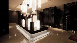A modern lobby with a central light feature, a reception desk, and a patterned floor. - Hotel Benoa Resort (Kobe)