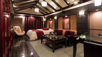 A hotel room with a bed, a massage chair, a coffee table, and a seating area with a table and chairs.