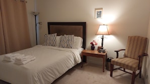 A hotel room with a bed, a chair, a nightstand with a lamp, and a picture on the wall. - Very  Spacious  , Cosy  and attractive 
 property. (Vaughan)
