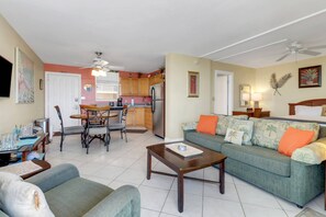 Un espace de vie compact comprenant un coin repas, un ensemble de canapés, une table basse et une kitchenette.