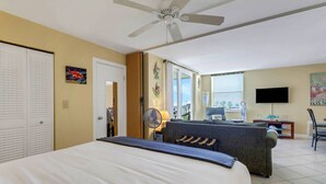 A hotel room with a bed, a sofa, a TV, and a ceiling fan. - GULF VIEW | 3RD FLOOR STUDIO | KING BED + QUEEN SLEEPER | FREE WIFI | STEPS TO BONITA BEACH (Bonita Springs)