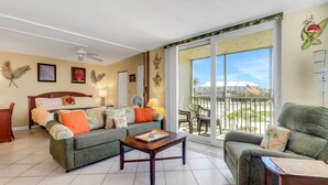 A spacious living room with a bed, two sofas, a coffee table, and a balcony with a view of the surroundings. - GULF VIEW | 3RD FLOOR STUDIO | KING BED + QUEEN SLEEPER | FREE WIFI | STEPS TO BONITA BEACH (Bonita Springs)