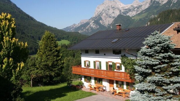 Eine Berglodge mit Balkon, Holzmöbeln und Blick auf die umliegenden Berge.